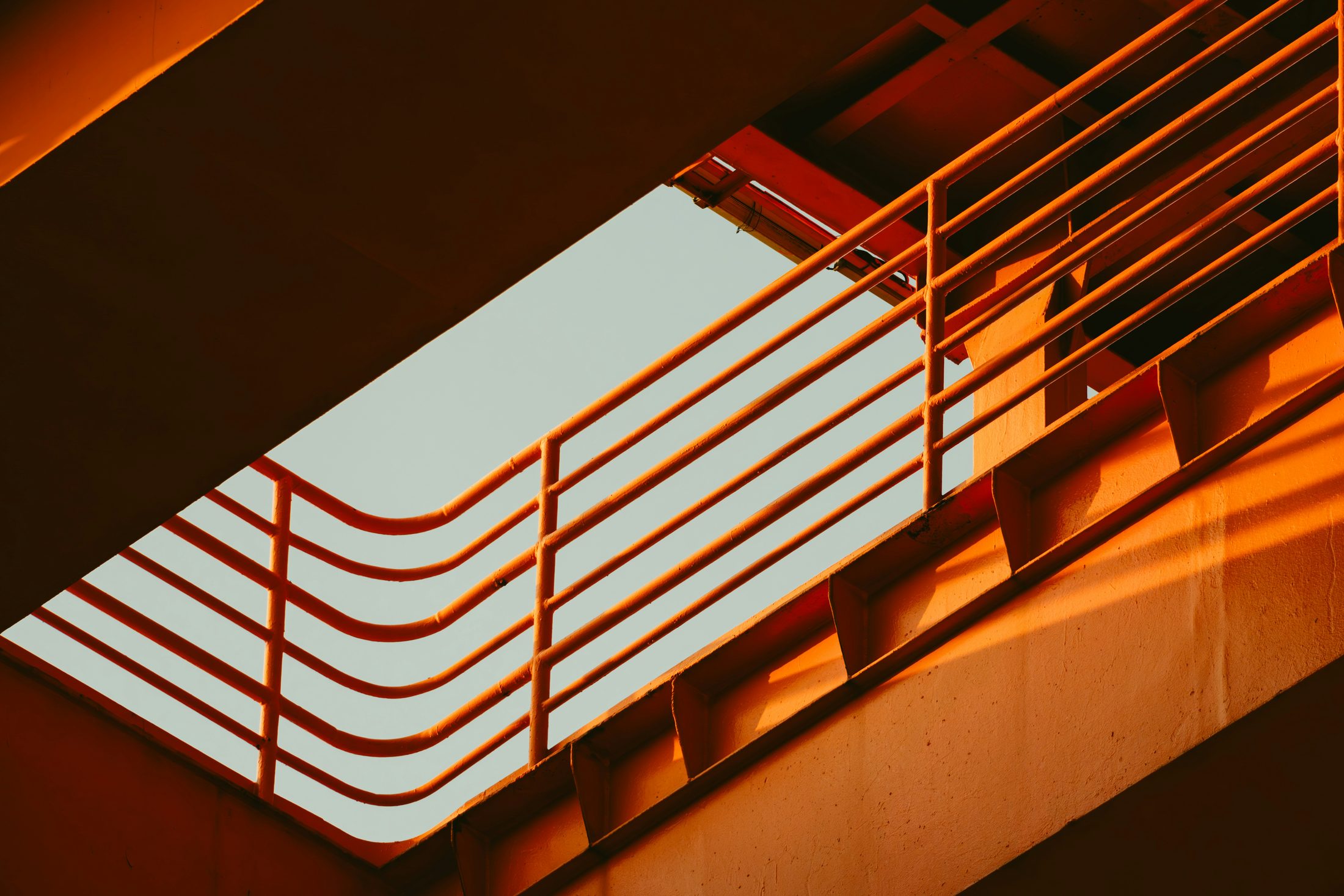 Warm, golden-hour architectural detail of curved metal railings and beams